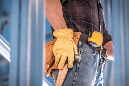 Getting Construction Job Concept Photo. Worker with Tools Belt Large Hammer and Measuring Tape. Closeup Photo.の写真素材