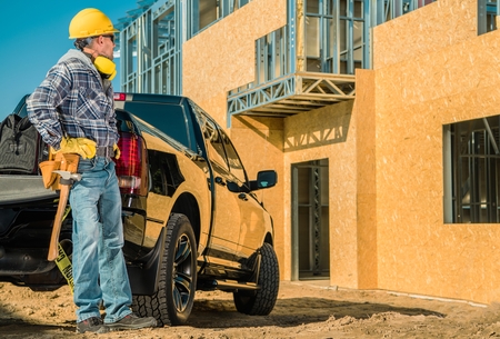 Residential Construction Site. Young Caucasian Contractor Worker in His 30s and His Pickup Truck in...