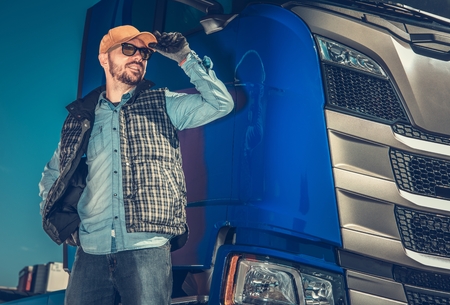 Semi Truck Driver and Hit Modern Vehicle. Happy Caucasian Trucker in His 30s. Transportation Industry.の写真素材