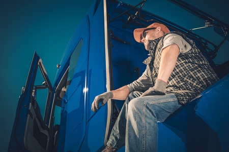 Truck Driver Cargo Transport. Caucasian Men Seating on His Semi Tractor and Enjoying the View.の写真素材