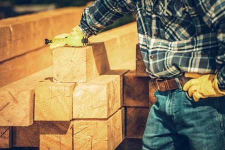 Wood Beams Material. Construction Worker with Measuring Tape Preparing For the Woodwork.の写真素材