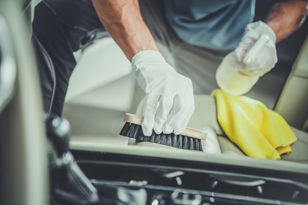 Car Seats Cleaning Using Brush. Caucasian Worker and Vehicle Detailing.