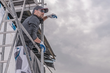 Construction Industry Theme. Caucasian Construction Worker in His 30s on the Metal Scaffolding.の写真素材
