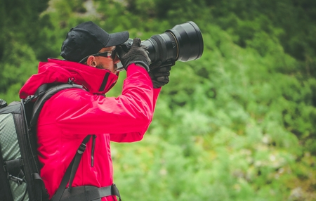 Caucasian Nature Photographer with Large Telephoto Lens Taking Outdoor Pictures.の写真素材