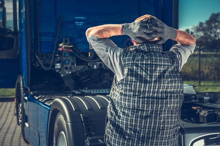 Depressed Truck Driver Having Big Problem with Broken Semi Truck Tractor. Transportation and Automotive Industry Concept.の写真素材