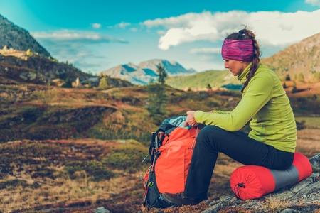 Trailhead Rest Stop. Young Caucasian Woman with Backpack on the Alpine Trail. Summer Time Hiking.の写真素材