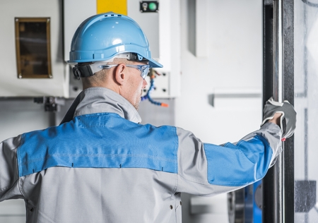 CNC Machinery Technician. Caucasian Metalworking Worker in His 30s in Front of Computer Numerical...