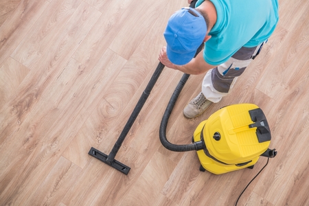 Caucasian Men Vacuuming Apartment New Hardwood Floor. Home Cleaning Time.の写真素材