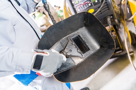 Welding Mask in a Hand. Welder and His Safety Equipment. Metal Industry Theme.