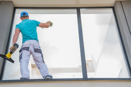 Caucasian Men Cleaning Large Residential Window Outside of the House. Cleaning Service Business.