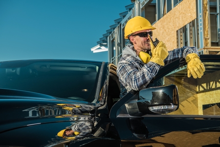 Happy Caucasian Contractor in His 30s Taking Conversation with Crew Member via Walkie Talkie....