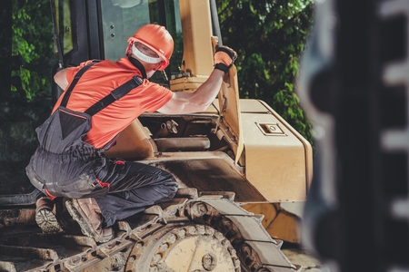 Mechanic and the Bulldozer. Caucasian Heavy Equipment Worker in His 30s. Industrial Theme.