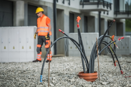 High Voltage Cables Installation. Bunch of Cables Comping From Underground Pipeline. Electric Technician in the Background.の写真素材