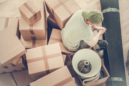 Caucasian Men Moving Out After Divorce. Seating on a Boxes with His Staff Awaiting Moving Company.