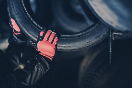 Choosing Right Car Tires. Automotive Industry Concept. Auto Service Worker Taking Out Modern Tire From a Rack.の写真素材