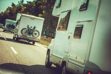 Camper Vans Traffic. Many RV Recreational Vehicles on the Same Road. Summer Time Vacation in a Motor Home.の写真素材