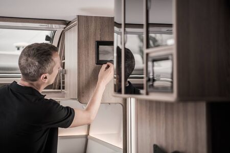Recreational Vehicle RV Computer Data Display. Caucasian Men in His 40s Checking Black and Gray Tanks Level Using On Screen Information Inside His Modern Travel Trailer.の写真素材