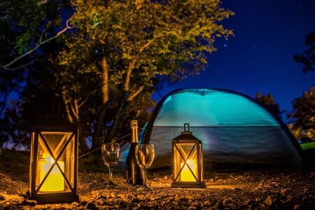 Romantic Camping Night with Bottle of Good Prosecco, Two Glasses, Candle Lanterns and Starry Night. Scenic Getaway with Extras.の写真素材