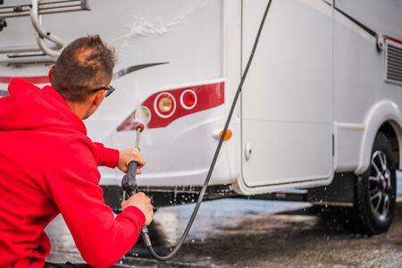Caucasian Men in His 30s Cleaning Outside His RV Camper Van Using Pressure Washer.の写真素材