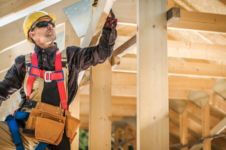 Wood Frame House Building Technologies. Caucasian Construction Contractor in His 30s. Industrial...