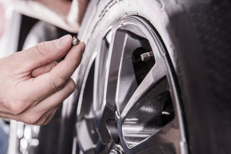 Caucasian Men Checking RV Recreational Vehicle Tire Pressure. Closeup Photo.の写真素材