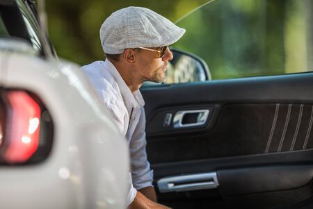 Young Caucasian Men Wearing Stylish Beret and Sunglasses Seating Inside His Modern Convertible Car and Enjoying the Moment.の写真素材
