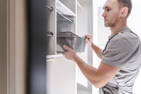 Caucasian Men in His 30s Finishing His Newly Remodeled Closet. Home Improvement Theme.