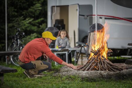 RV Camping Campfire in Front of Motorhome Pitch. Summer Vacation with Motorhome. Caucasian Family.の写真素材