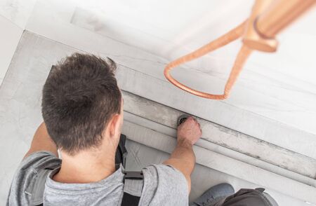 Installing Modern Linear Shower Drain. Bathroom Interior. Caucasian Plumbing Technician at Work....