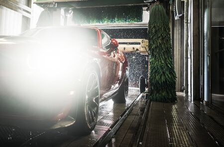Automotive Industry. Cleaning Car in Automatic Brush Indoor Car Wash. Late Evening Vehicle Maintenance.の写真素材