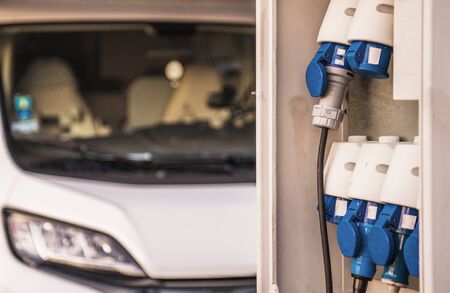 RV Park Camping Electric Pitch Hookups Closeup. Motorhome in the Background. 