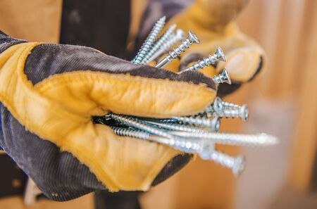 Metal Construction Screws in Workers Hands Closeup Photo. Industrial Theme.