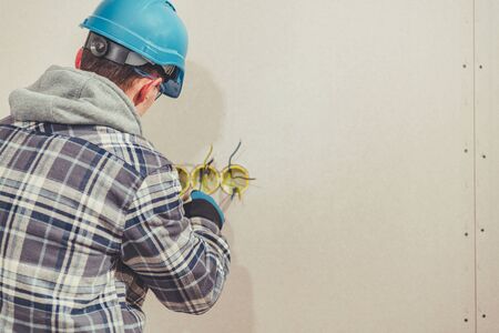Caucasian Electrician Sorts Out Wires Preparing For Plug Installation In Walls.の写真素材