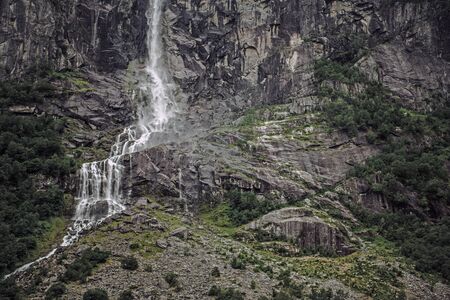Norwegian Steep Rocky Mountains With Waterfall And Short Bushes. 