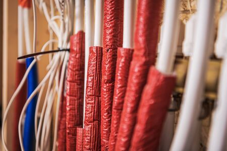 Residential Floor Heating Pipelines Covered by Red Insulator Close Up. Heat Pump Industrial Theme.