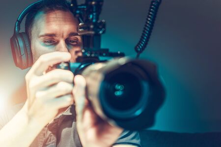Caucasian Video Camera Operator at His 30s Taking Movie Shots Using Modern DSLR Video Camera. Videographer at Work.の写真素材