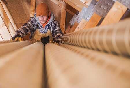 Industrial Theme. Residential Air Ventilation Pipelines Prepared by Caucasian Technician Worker. Home Air Quality.の写真素材