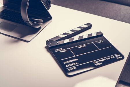 Vintage Black And White Clapperboard with Laptop Computer And Wireless Headphones On Table. の写真素材