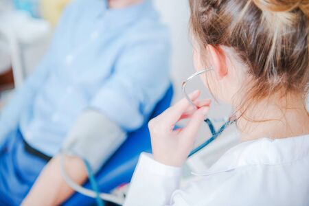 Female Doctor Assistant With Stethoscope Checking Patient Blood Pressure At Clinic. の写真素材