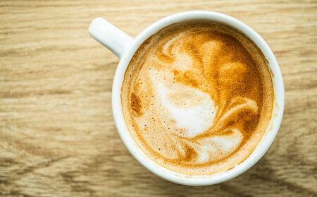 Cup of Fresh Cappuccino on Wooden Table Top View Photo. Made by Professional Barista.