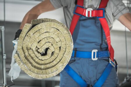 Roll of Insulation Mineral Wool Material Moved by Air Climate Control Caucasian Worker.