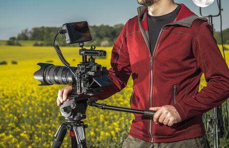 Videographer Camera Operator with Professional Digital Recording DSLR Camera on a Tripod. 