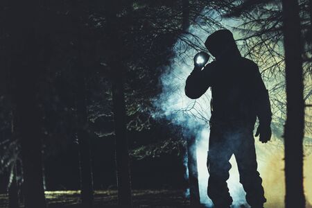 Mysterious Men with Flashlight in His Hand In Dark Foggy Forest. Poacher, Hunter or Rescuer During...