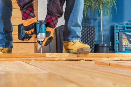 Men Building Wooden Porch Attaching Wood Planks Elements with Large Screws Using Cordless Driver. Small Wooden Garden Projectの写真素材