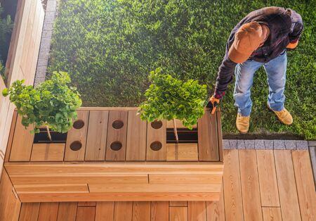 Carpenter Putting Finishing Touches On Creative Wooden Table And Deck Project In Residential Backyard Area. の写真素材