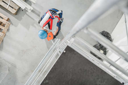 Caucasian Contractor Worker Installing Counter Weight on Aluminium Scaffolding For the Best Weight Distribution While in Useの写真素材