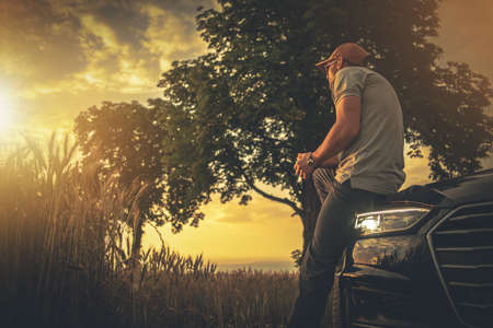 Caucasian Men Wearing Baseball Hat in His 40s Relaxing During Car Road Trip and Enjoying Summer Time...