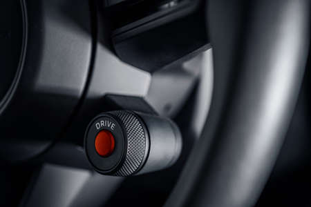 Supercar Engine Ignition Red Push Button Start on the Vehicle Steering Wheel Close Up. Modern...