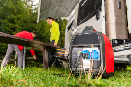 Modern Gasoline Powered Generator Running Next to Camper Van Recreational Vehicle. Powering RV Camping Pitch with Own Energy Source.の写真素材