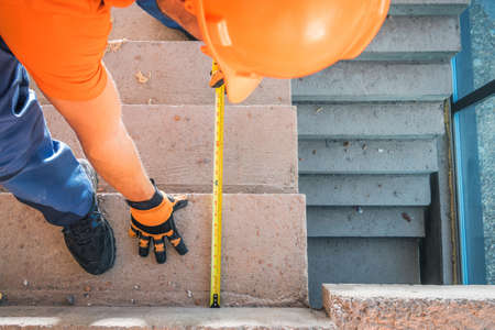 Caucasian Construction Contractor Measuring Concrete Building Steps. Residential Stairs Steps...